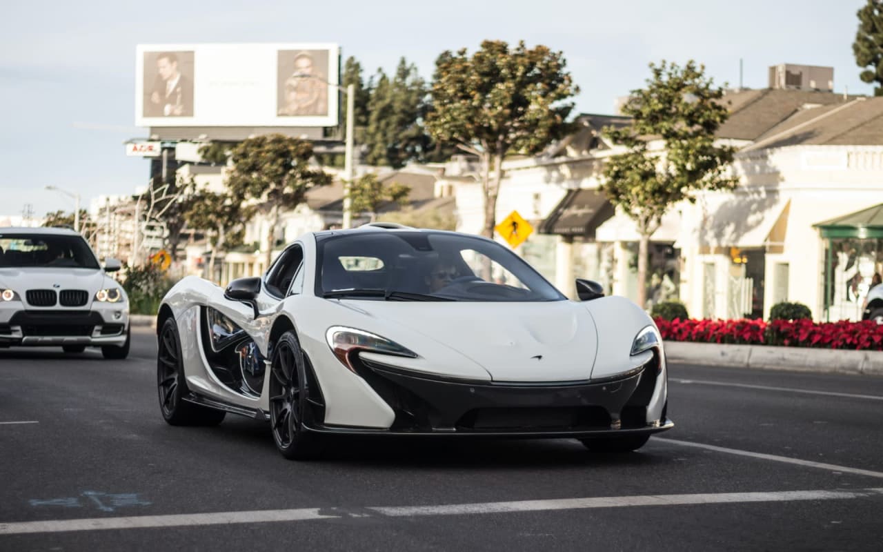 A white sports car driving down the city street