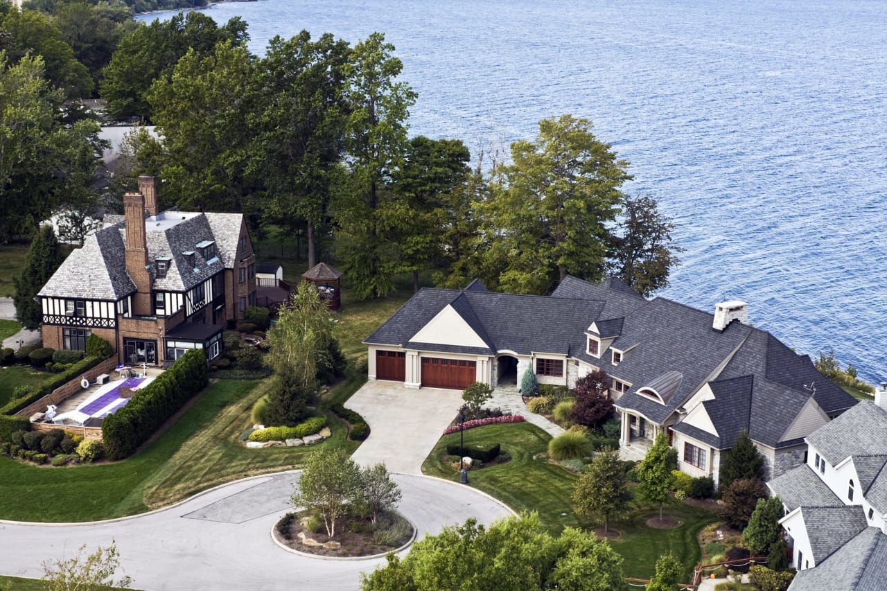 An aerial view of a luxury home with a swimming pool next to a bright blue ocean.