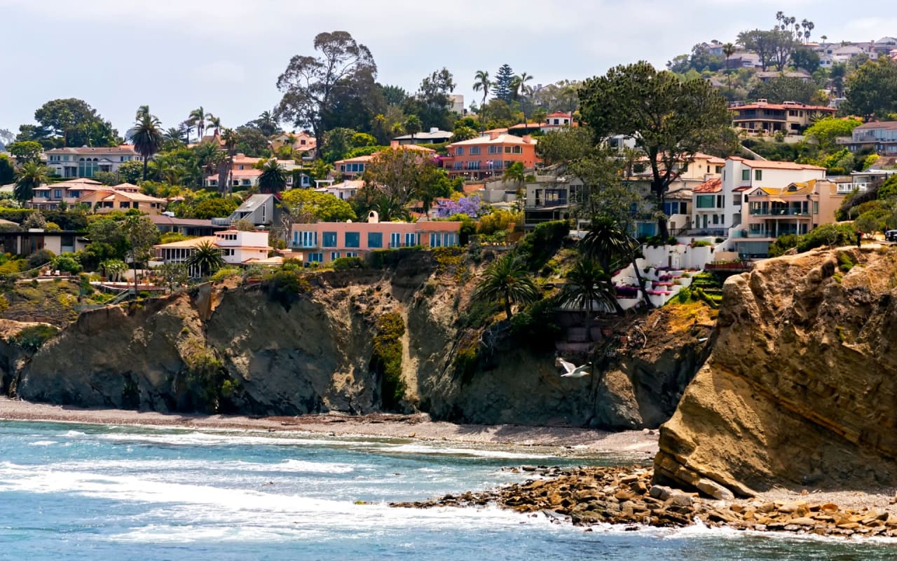 A group of houses sitting on top of a cliff, overlooking the ocean