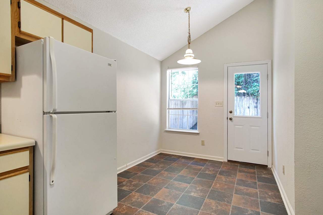 Photo of eat-in Kitchen Featuring vaulted ceilings, a drop light fixture, a window, access to the back patio, and modern-colored tiled flooring at 2709 Oak Park Court, Tallahassee, Florida 32308