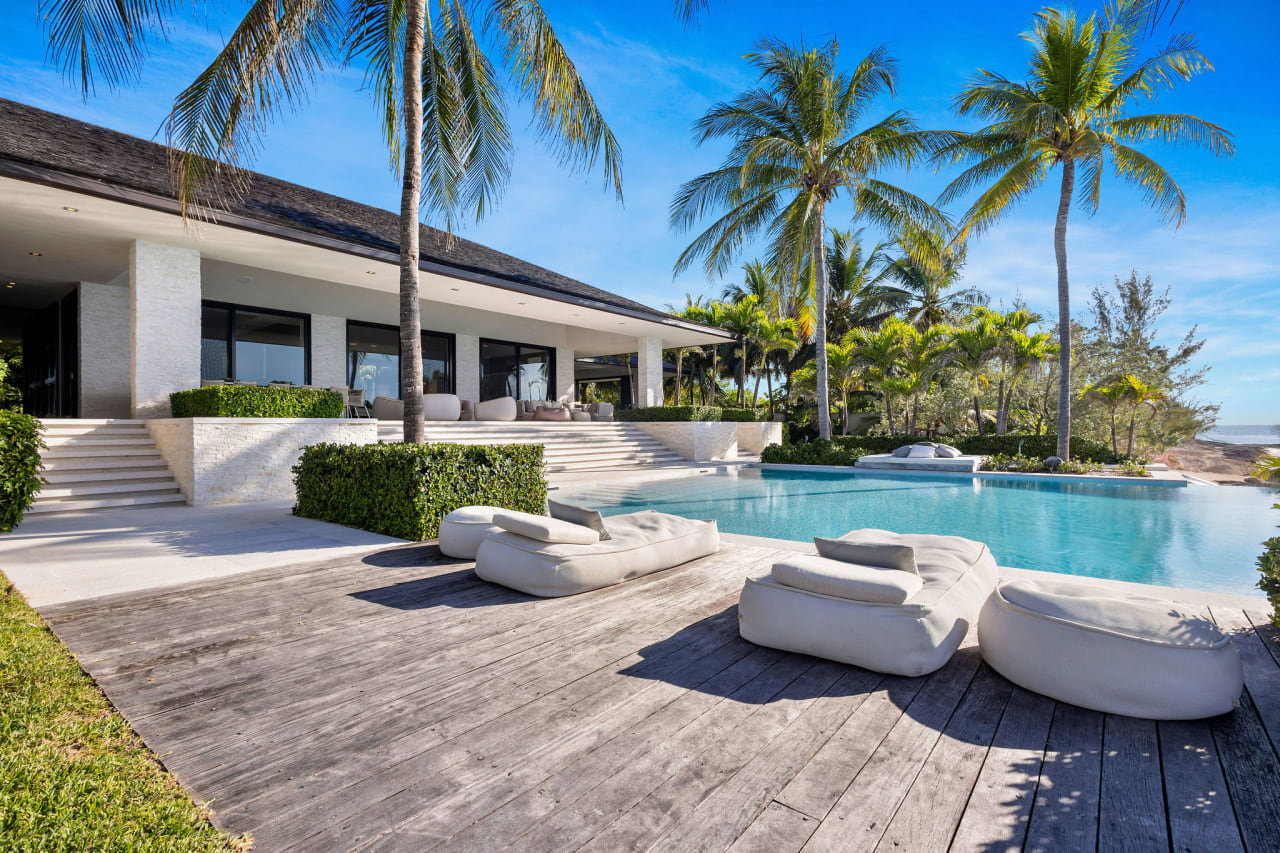 A large, rectangular swimming pool with a wooden deck and several lounge chairs next to it.