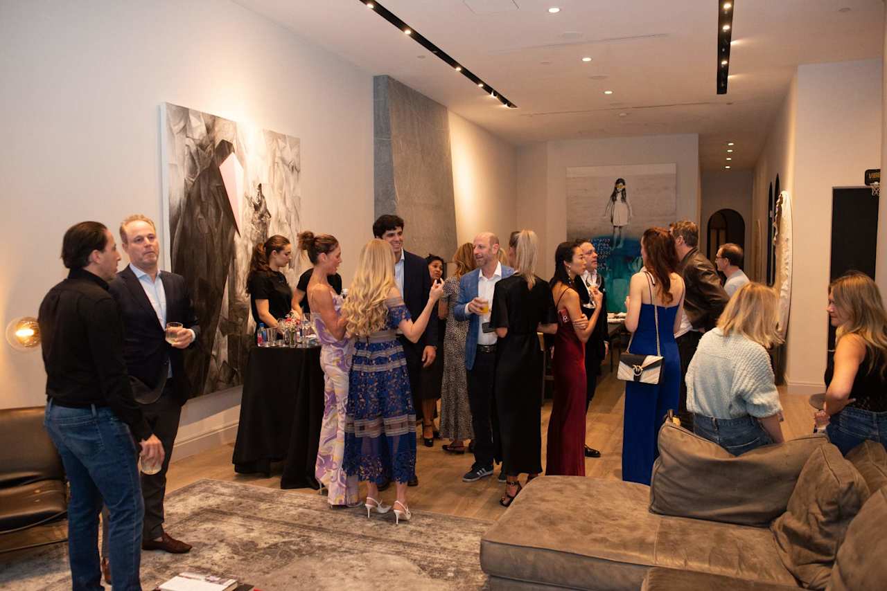 Guests mingle beside contemporary artwork and lounge seating at an indoor gathering.