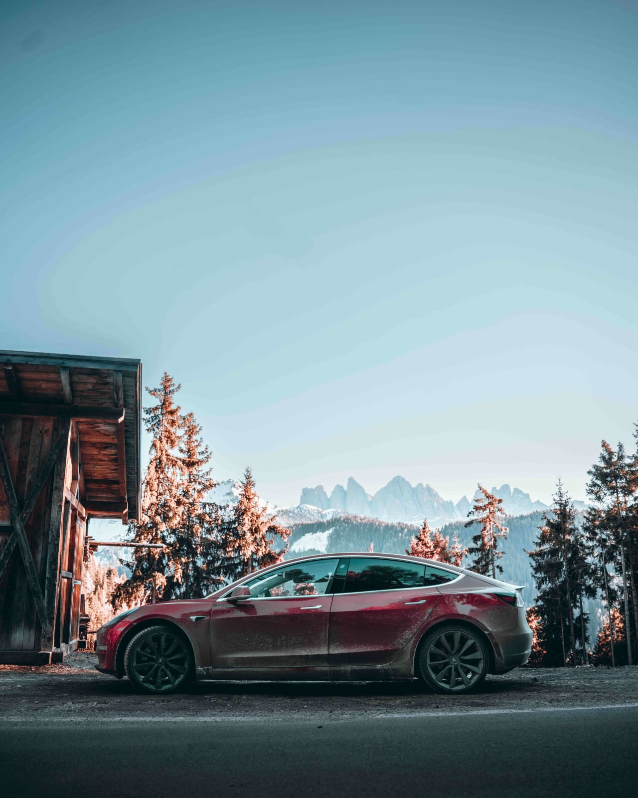 A Luxury Tesla parked on the side of the road with the rocky mountains in the background