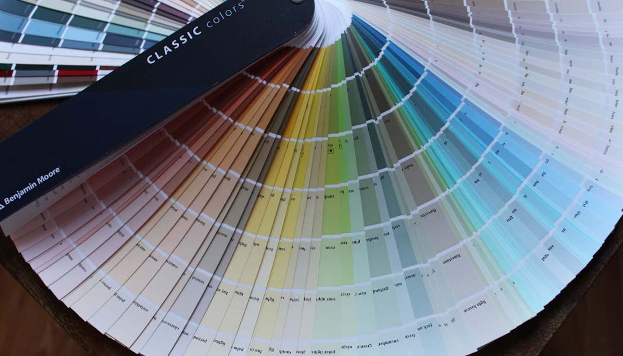 A Benjamin Moore Classic Colors fan chart showcasing a wide range of paint colors from warm neutrals to cool blues & greens.