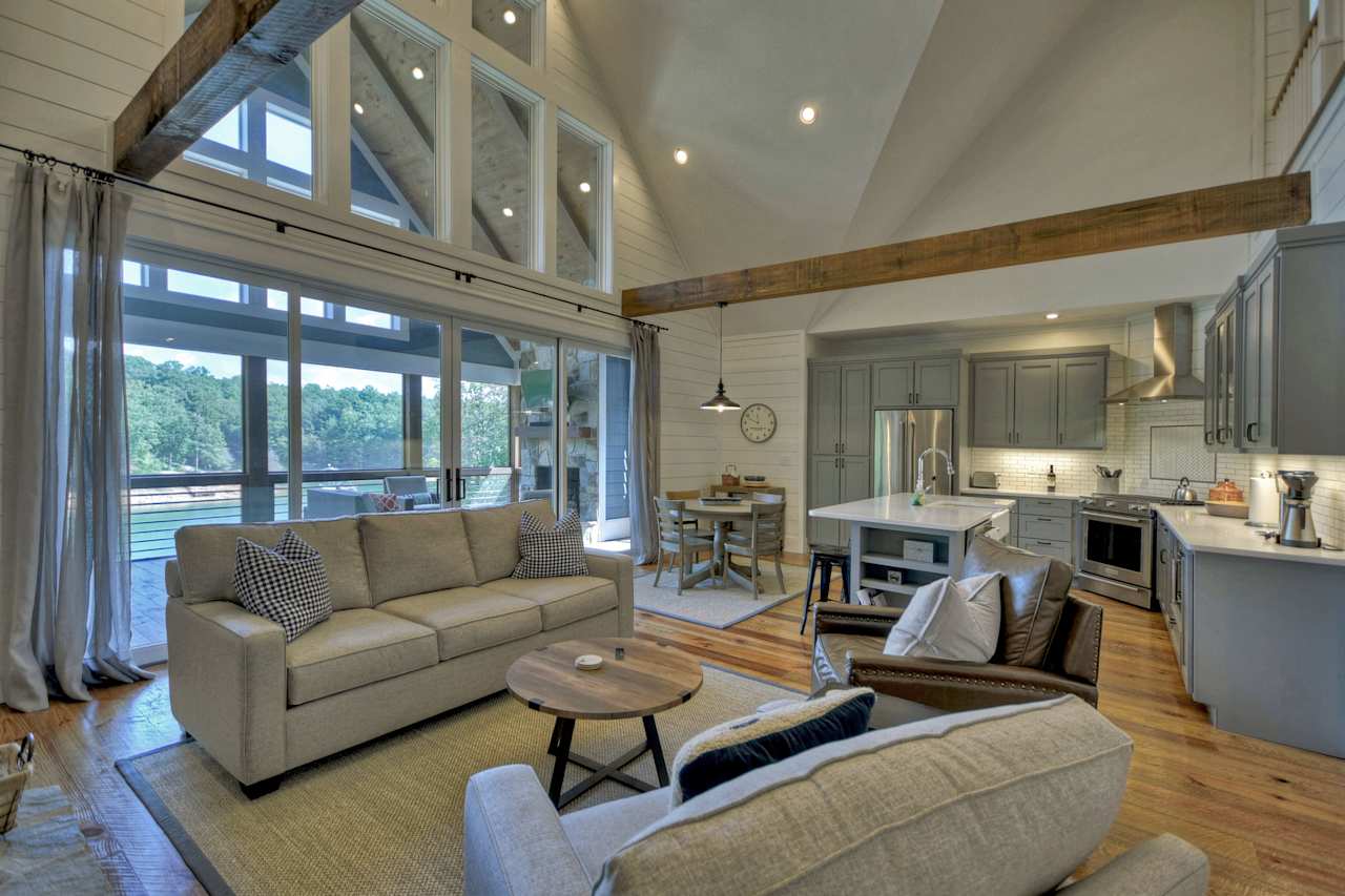 A cozy living room with a couch, two armchairs, and a coffee table next to an open kitchen.