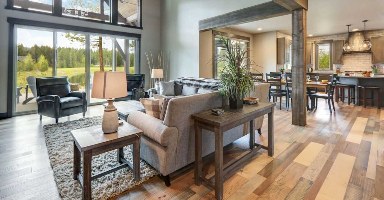 Open-plan living room with tall windows, a gray sofa, and hardwood floors.