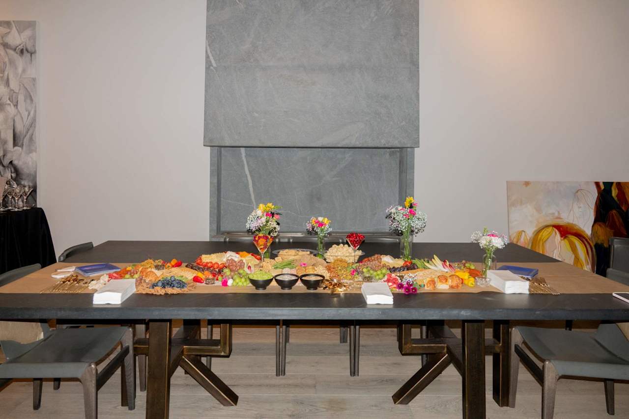 Catered buffet of charcuterie, cheeses, fruit, and desserts on a long dining table.