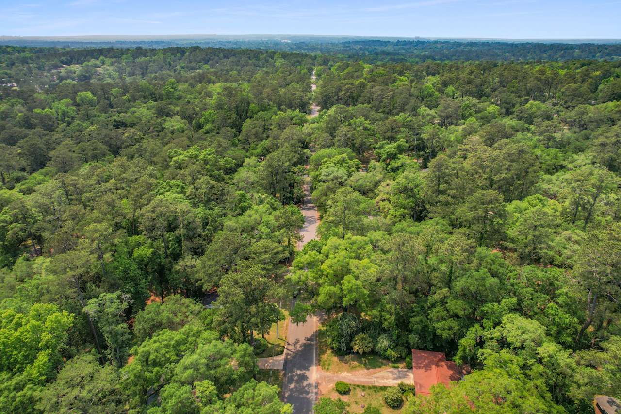 An aerial view of the Forest Heights Hollow community, showcasing houses surrounded by dense forest and natural landscapes.