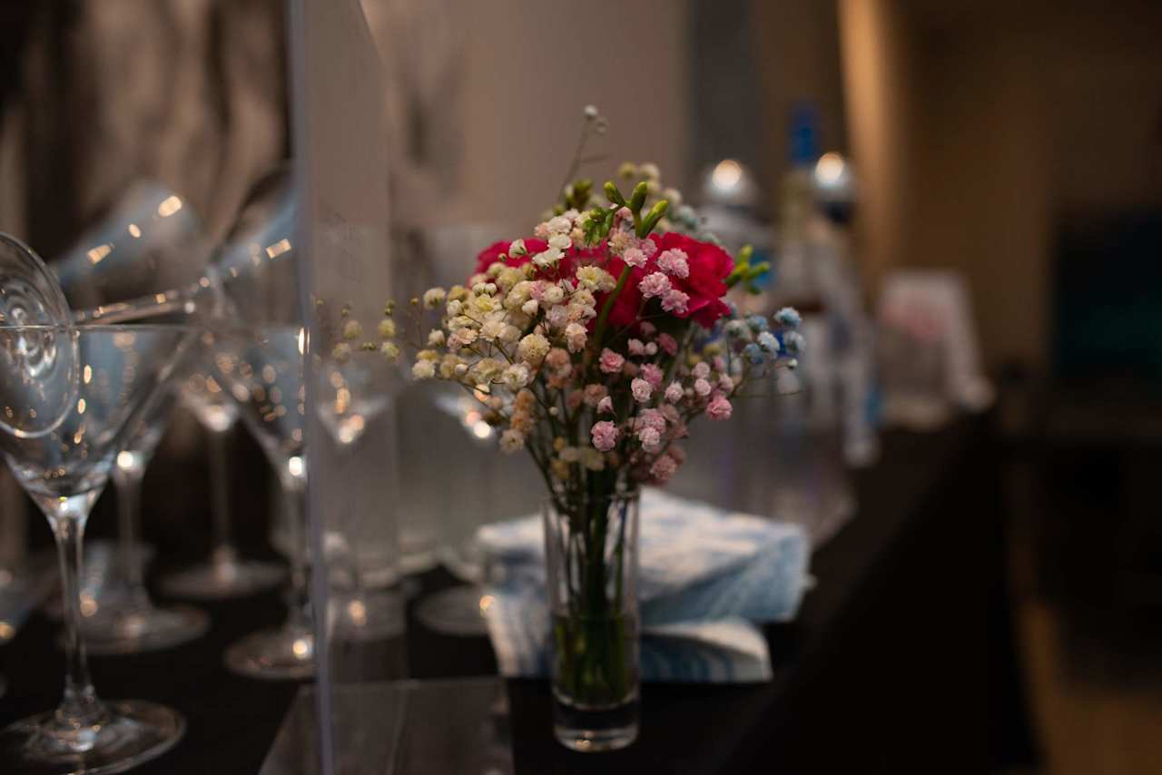Colorful flowers in a vase among wine glasses on an elegantly set event table.