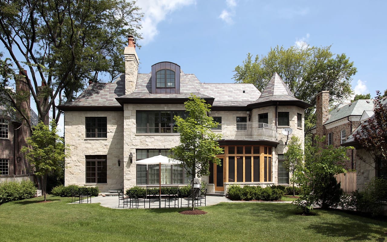 A large brick house with a stone patio in front of it