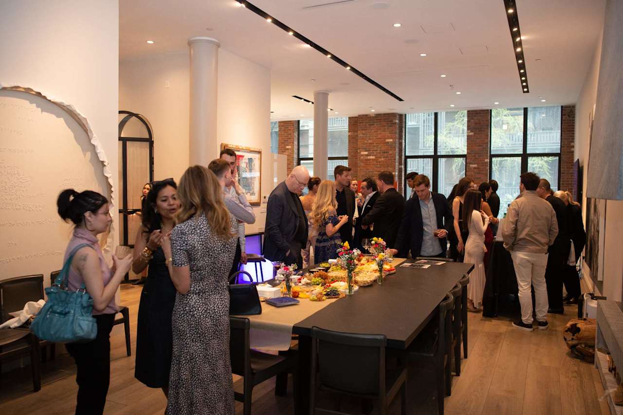 Guests mingle around a buffet table at a reception in a bright event space.