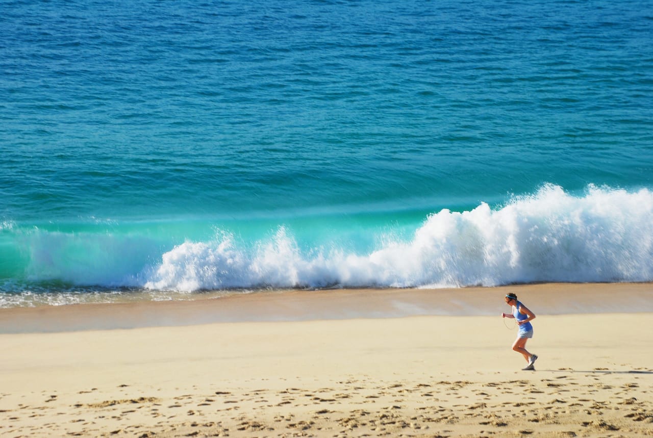 Expat woman from USA running near the shore on a white sand beach in Los Cabos