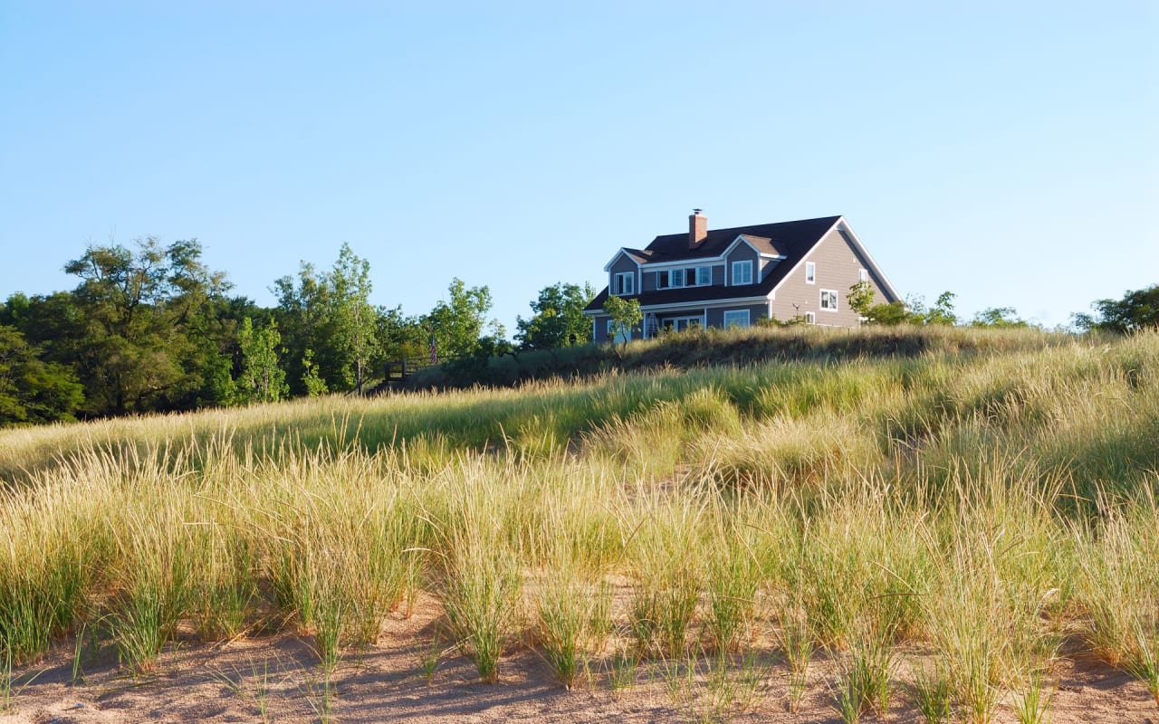 A house sitting on top of a hill surrounded by tall grass