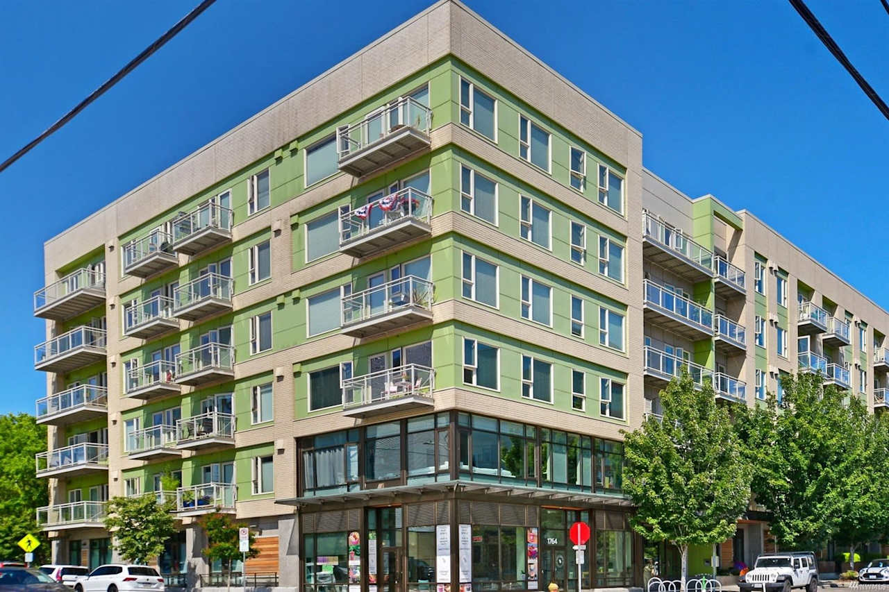 Modern urban condo with green accents under clear blue skies, offering contemporary city living.