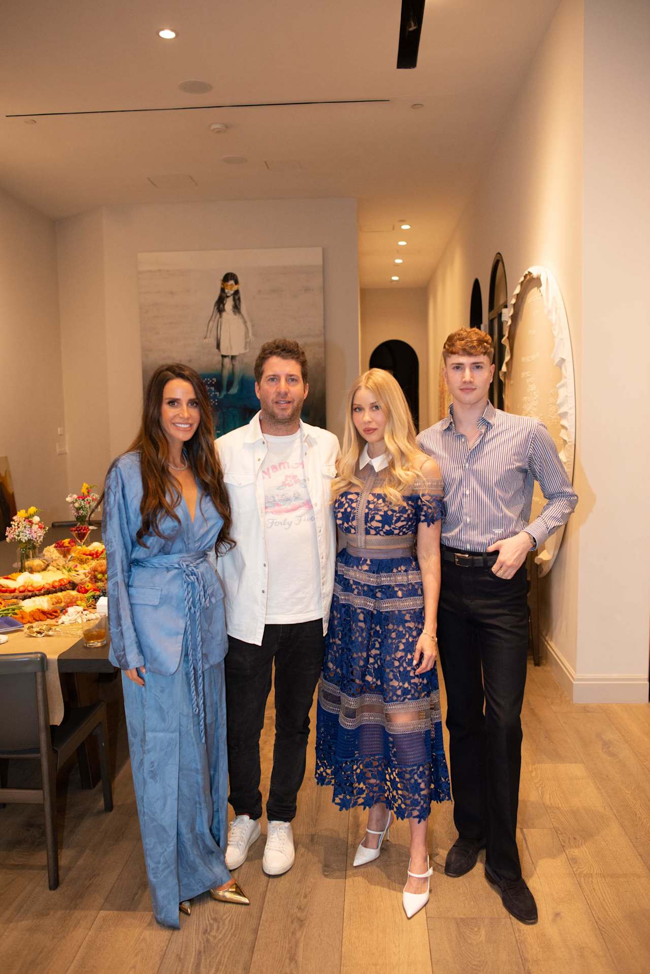 Four adults pose together at an indoor event beside a buffet table.