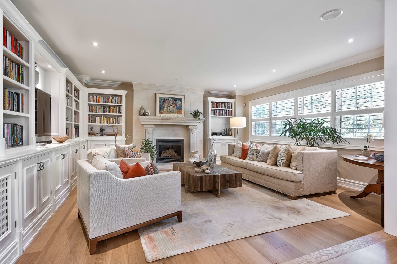 A spacious living room with a fireplace, a couch, two chairs, and a coffee table.