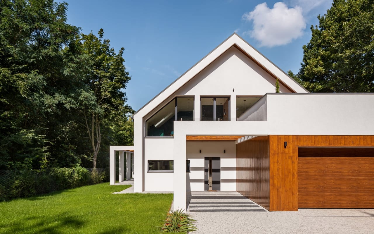 A white house with a brown wooden garage door. 