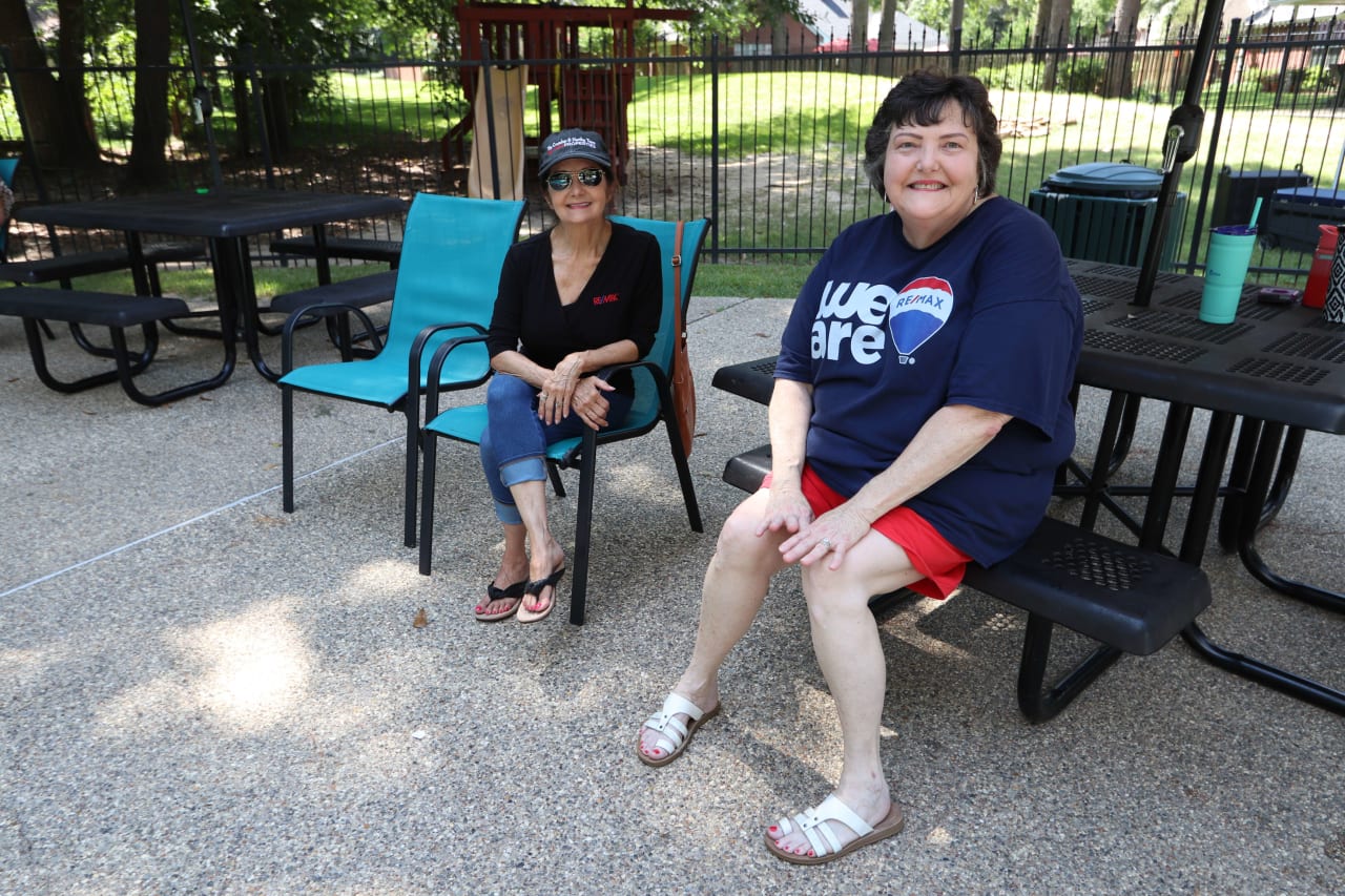 two people sitting on a chair in a park