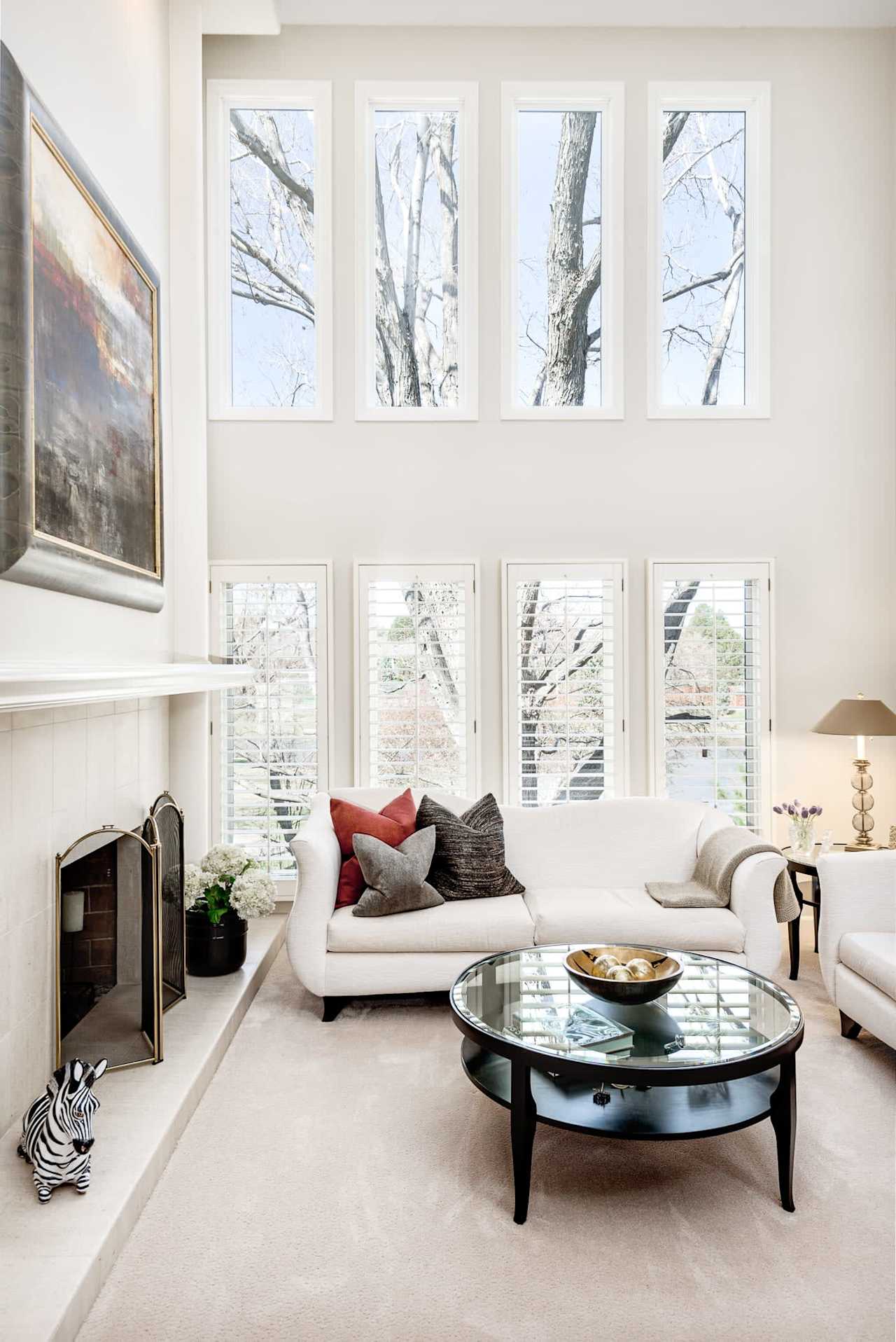 A cozy living room with a couch, coffee table, fireplace, and painting on the wall