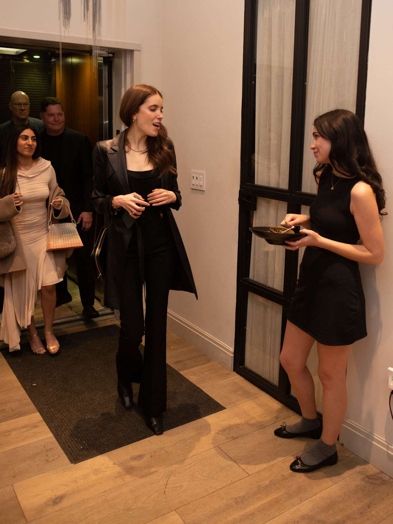 Guests mingle at an indoor event as a woman serves food to another attendee.