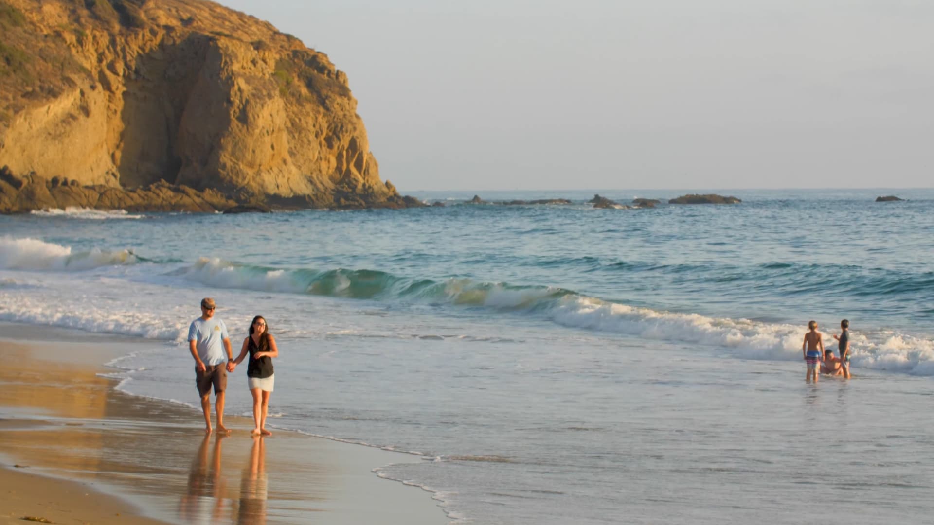 Couple walking holding hands on the beach by the water