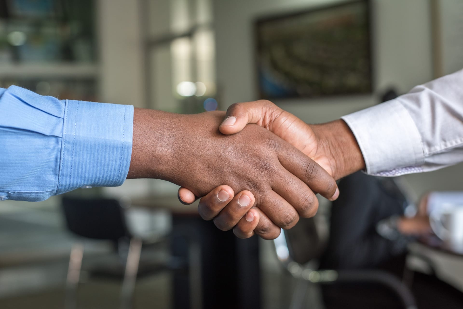 The hands of two men engaged in a handshake, symbolizing a professional agreement or partnership.