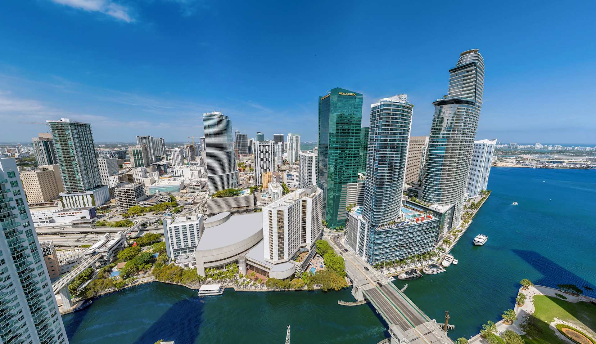 Aerial view of Brickell waterfront skyline, with high-rise towers and a bridge over Biscayne Bay.