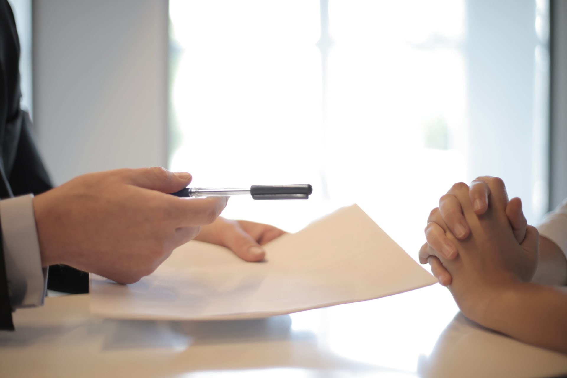 The hands of a real estate agent holding a pen, engaged in a discussion with a client.