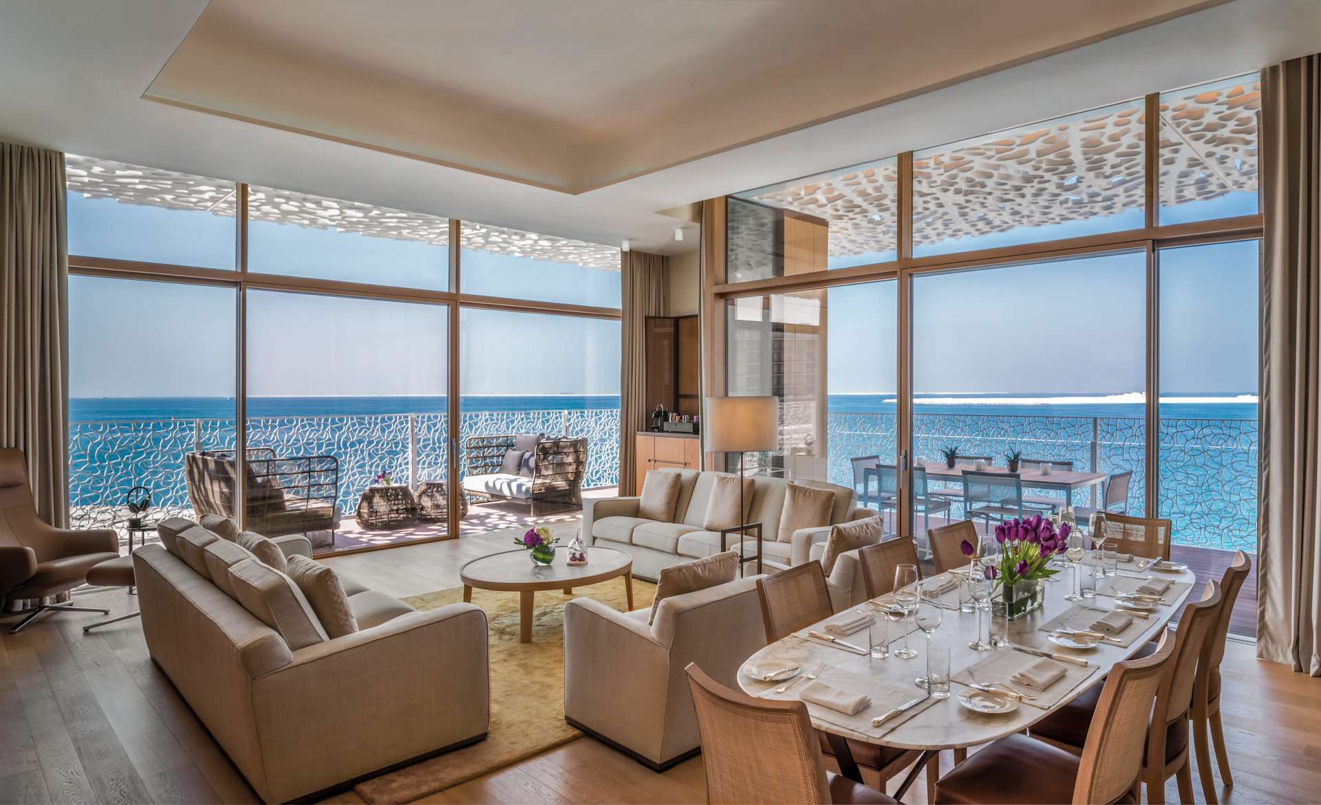 Oceanfront living and dining room with floor-to-ceiling windows and a balcony view.