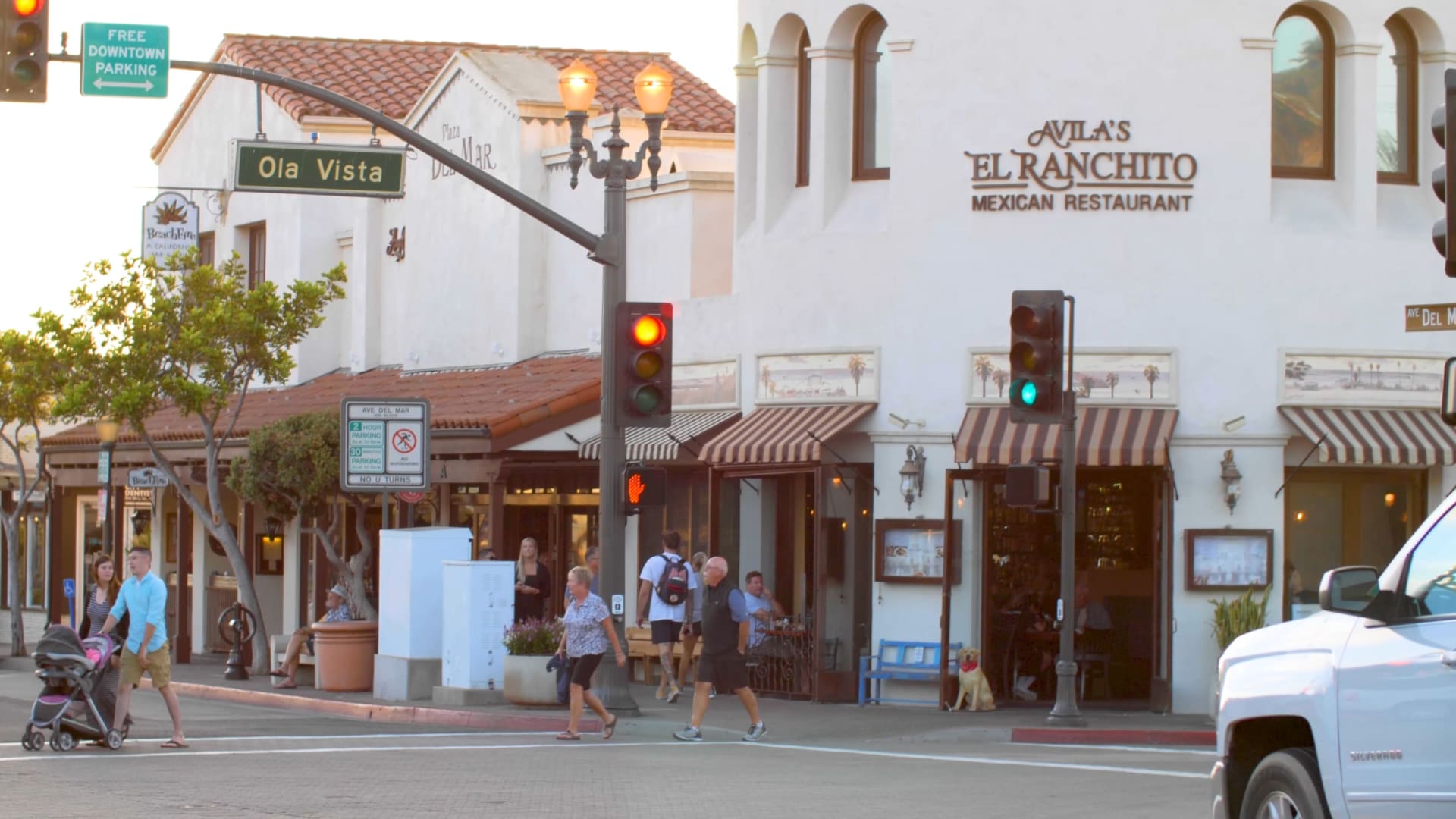 Busy street at stoplight with pedestrians walking by shops and restaurants