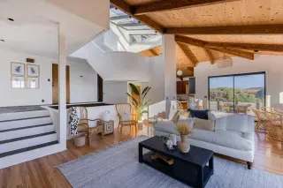 Open-plan living room with vaulted wood ceiling, skylights, and sliding glass doors.