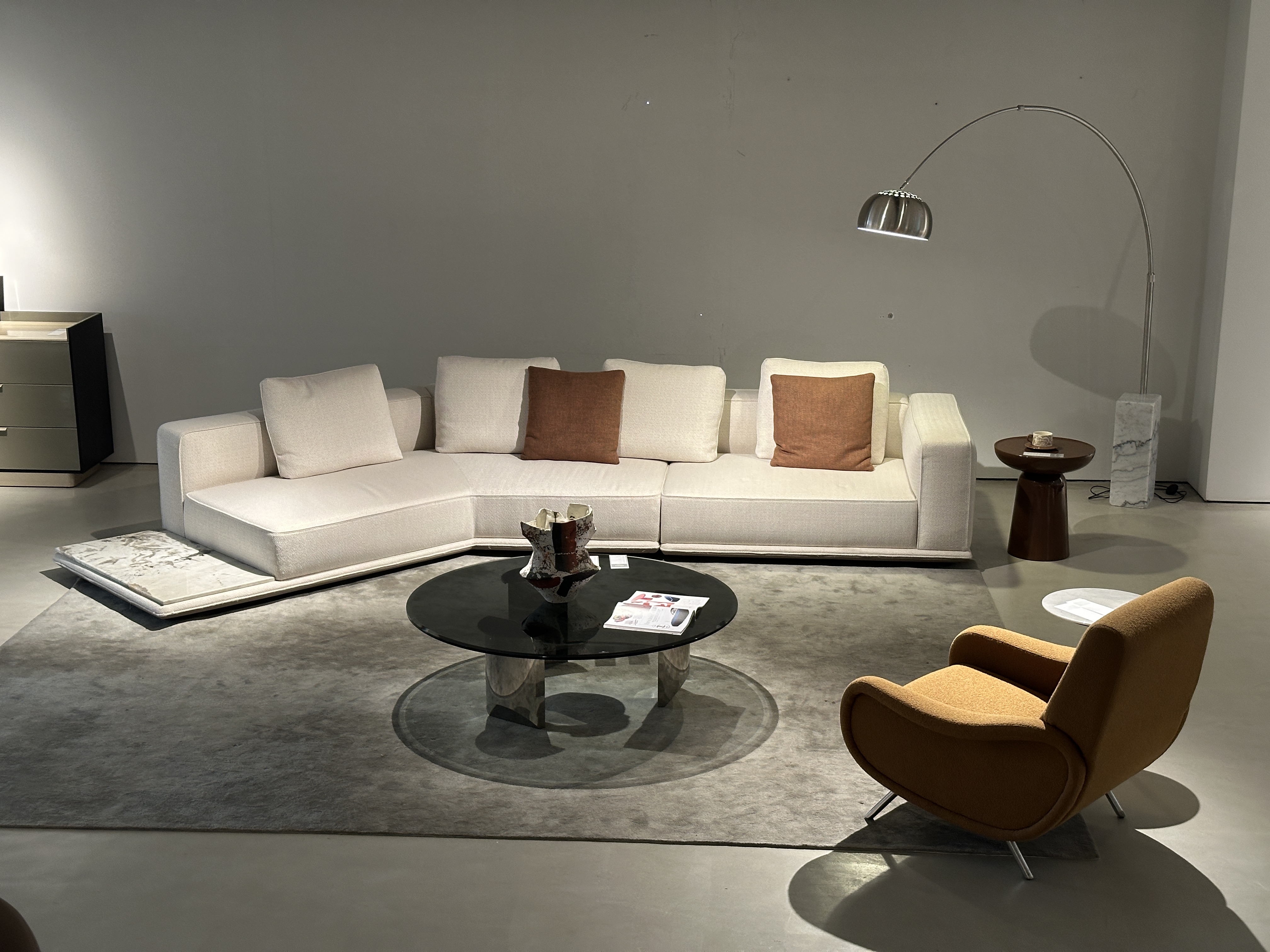 Architectural cream modular sofa on grey rug under a chrome arc lamp