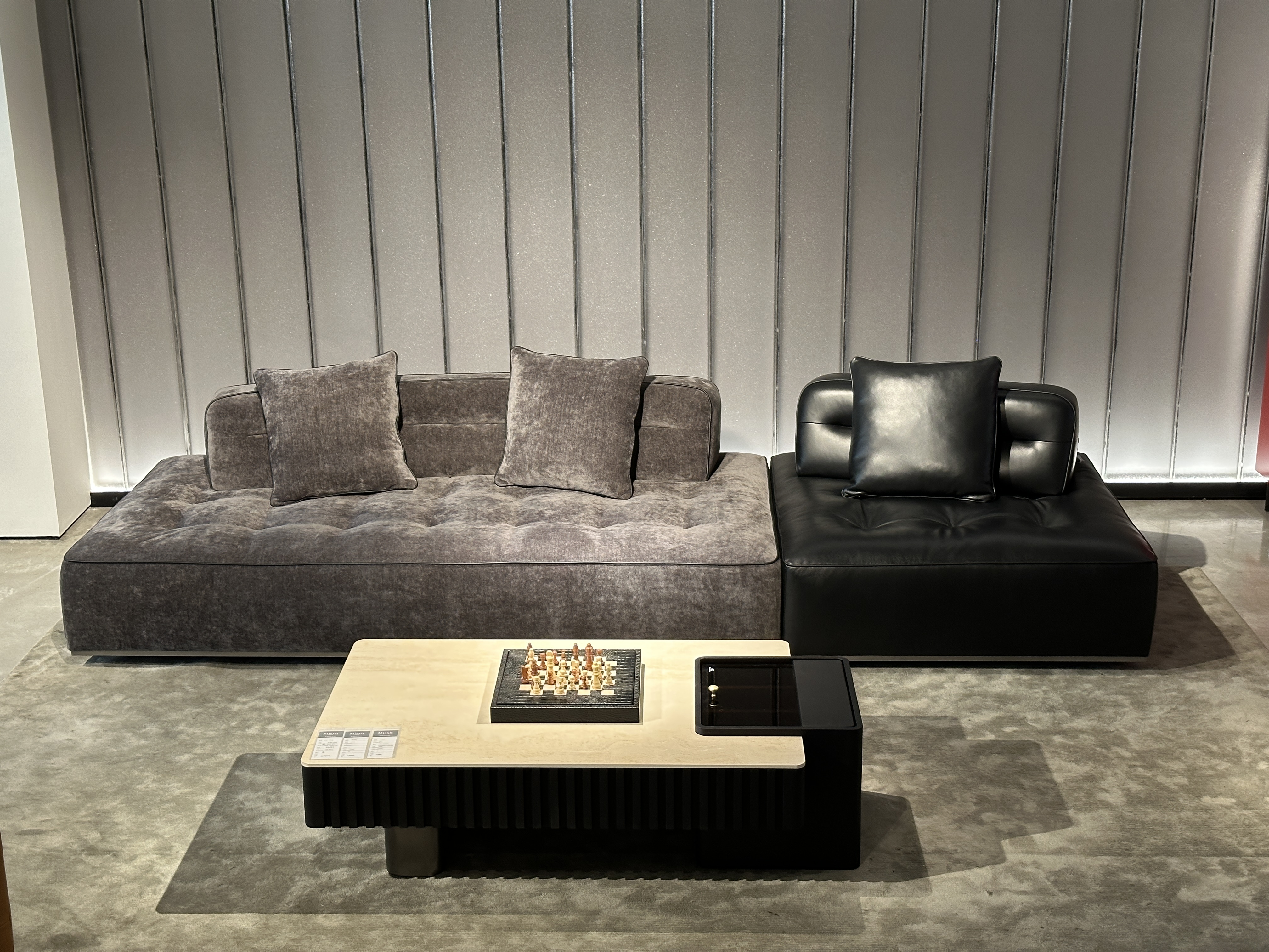 Low-profile tufted modular sofa with fabric–leather contrast facing a stone coffee table