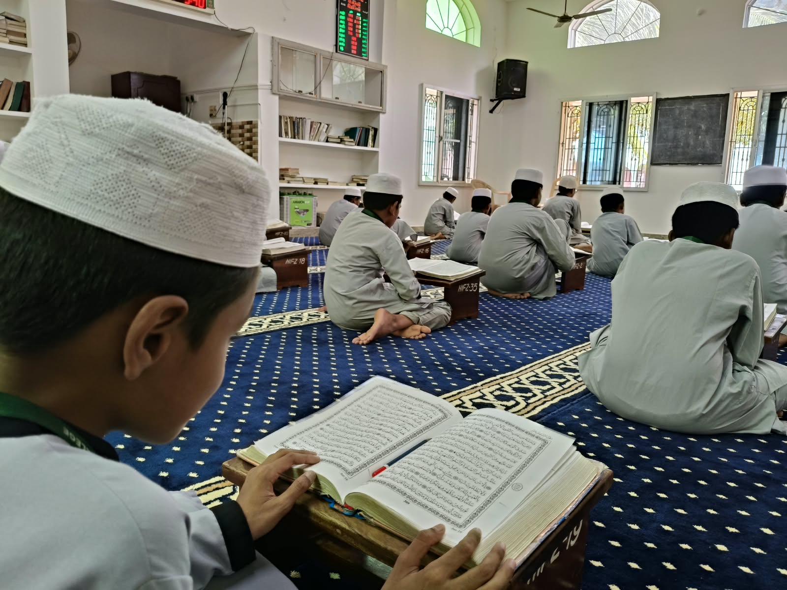 Open Quran resting on a wooden stand in a prayer hall