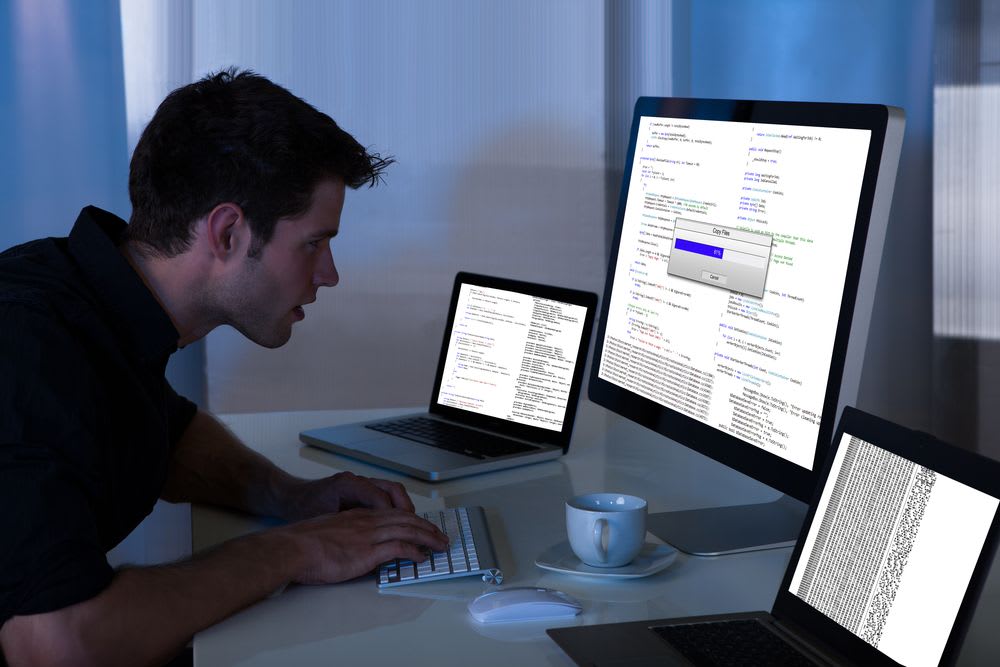 Man typing on a keyboard and looking intently at the computer screen.