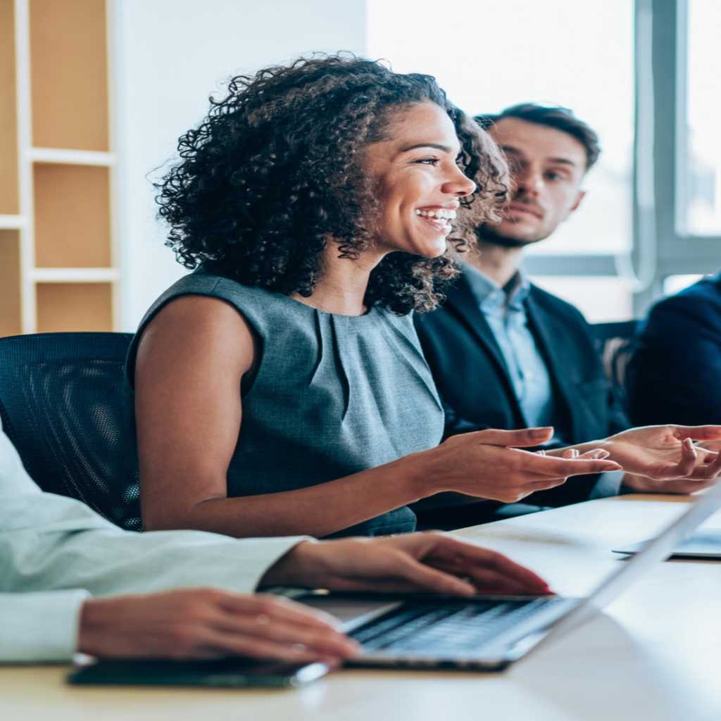 A woman smiles as she works collaboratively with business associates, one types on a keyboard to manage VPS