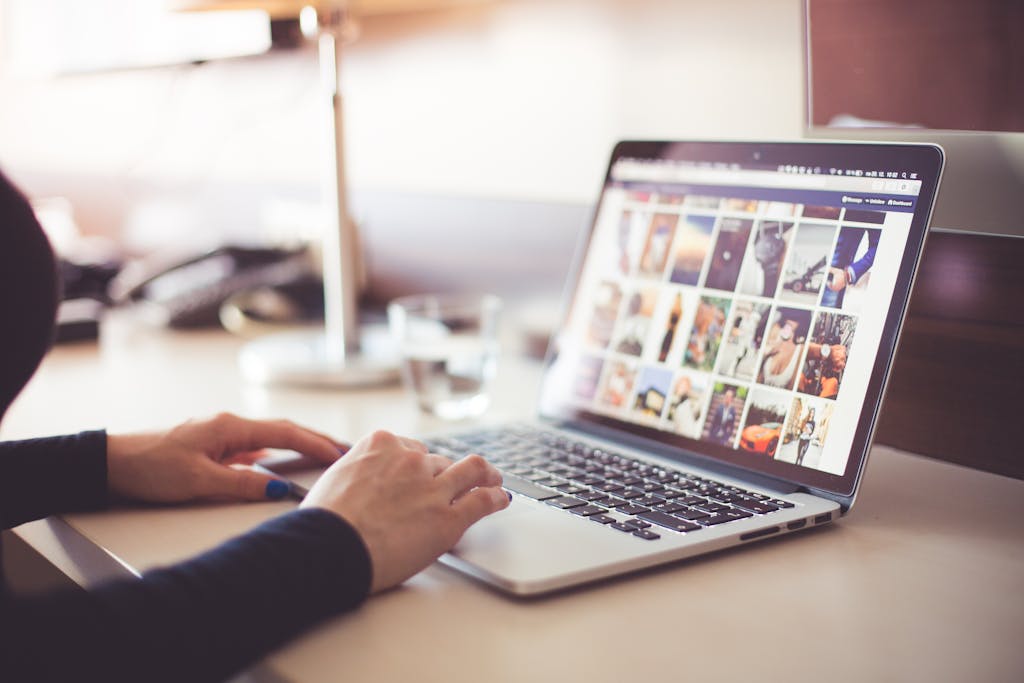 Person Using Laptop Computer to Look Through Images Suring Daytime