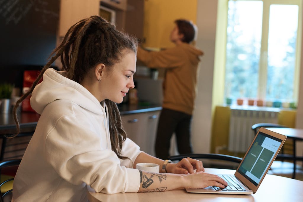 A freelancer uses a laptop in an office kitchen , she interacts with software