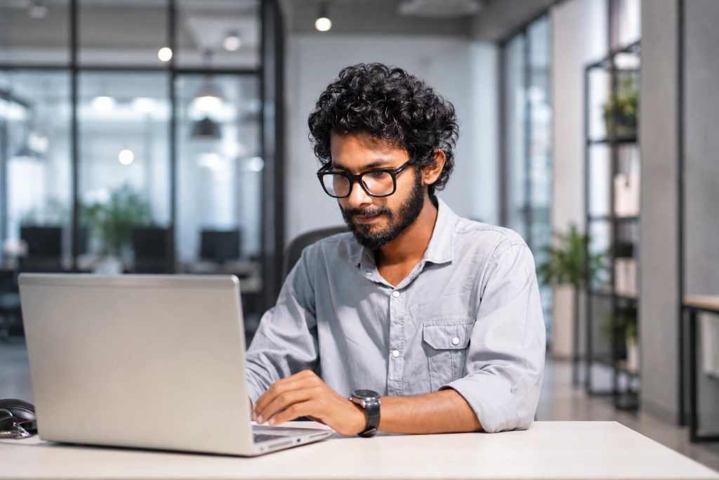 Man working on a laptop in a modern office setting.