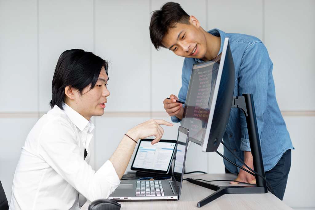 Two IT professionals reviewing technical information on a computer screen.