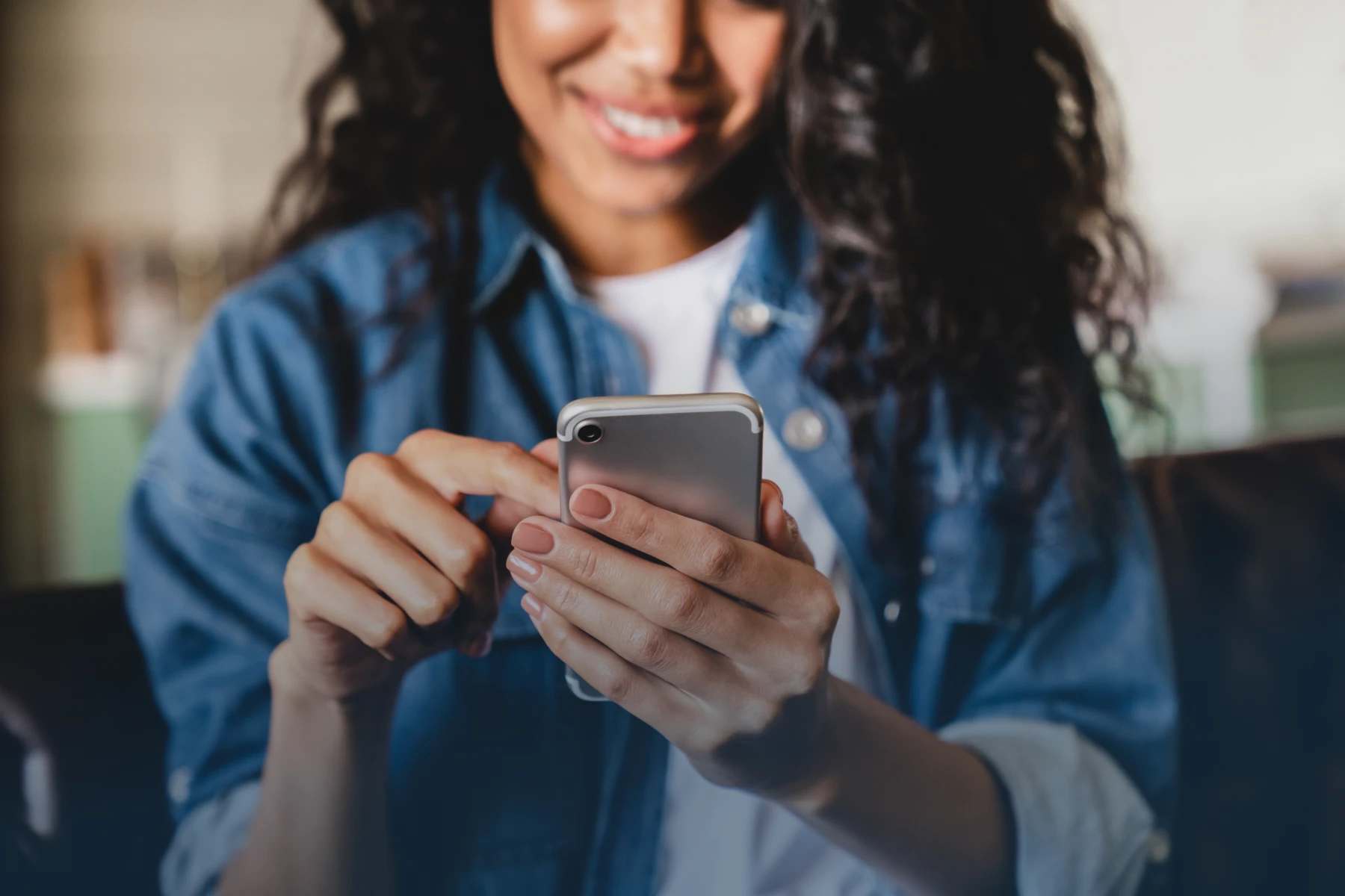 Photo of woman in jean jaclet looking at smart phone