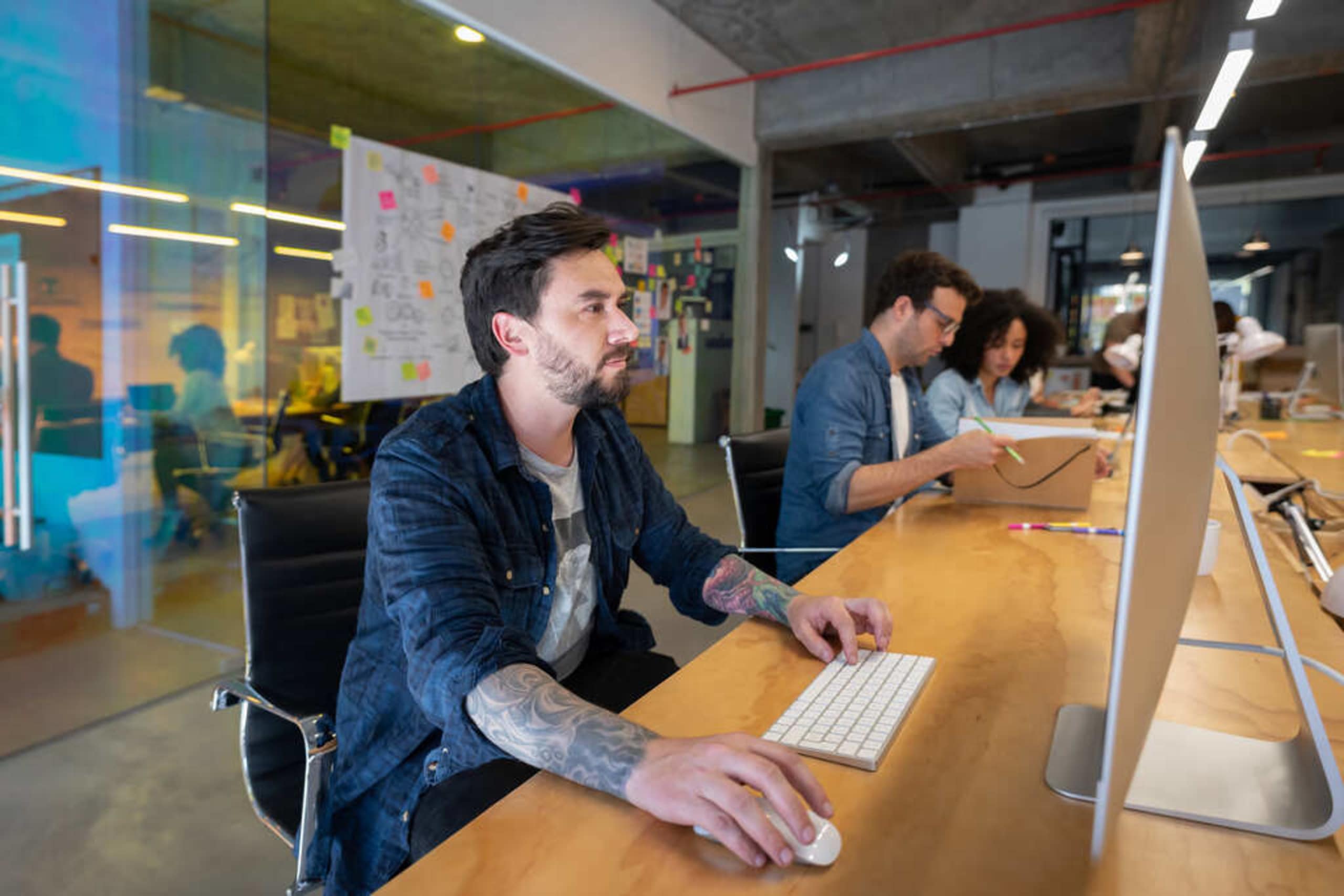 Latin American designer working at a creative office using his desktop computer - place of work concepts