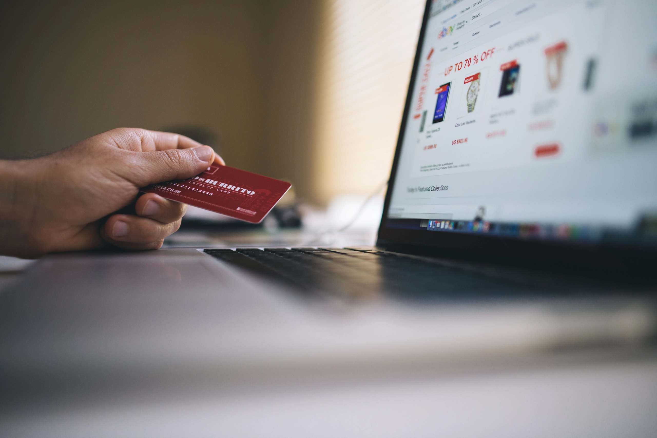 Person holding a credit card while shopping online on a laptop.
