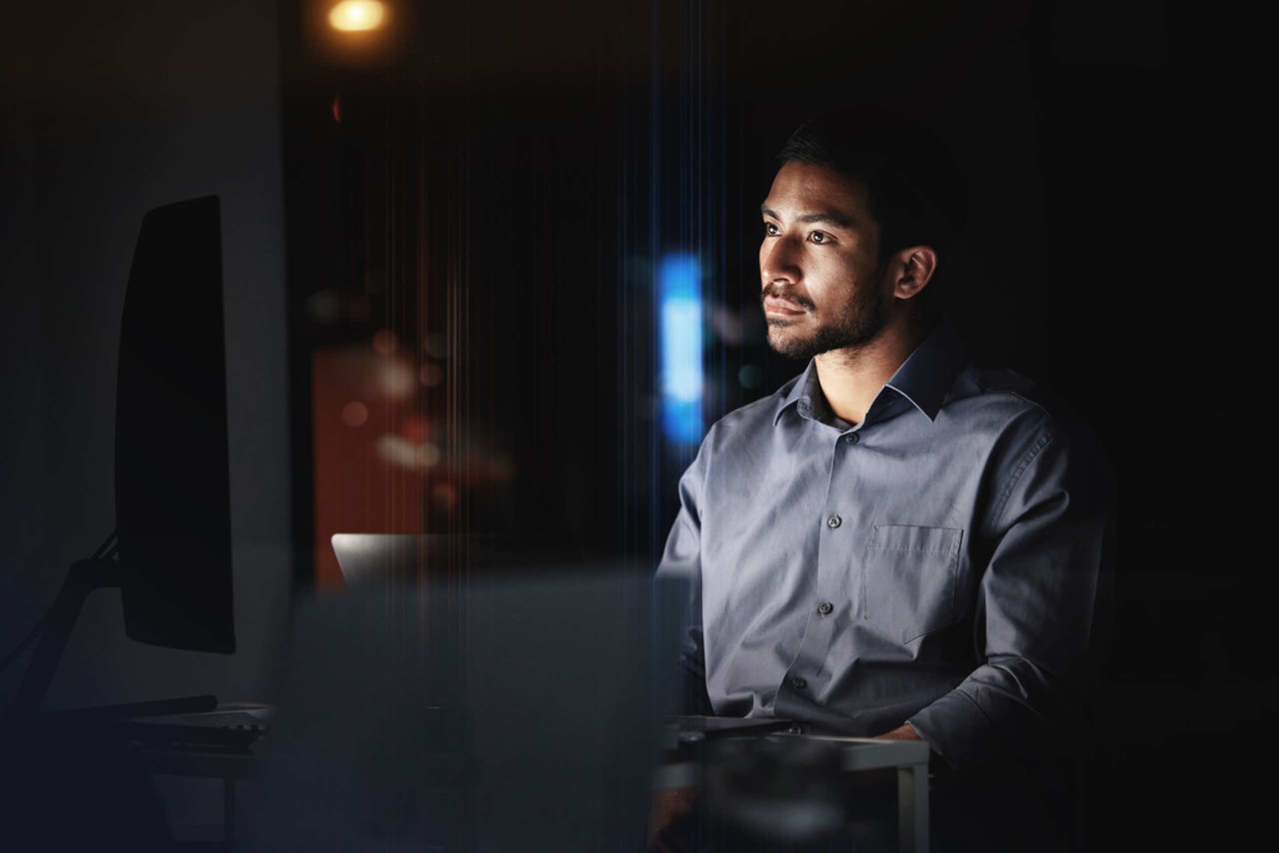 A man looks intently at a large computer monitor as he compares managed WooCommerce hosting plans