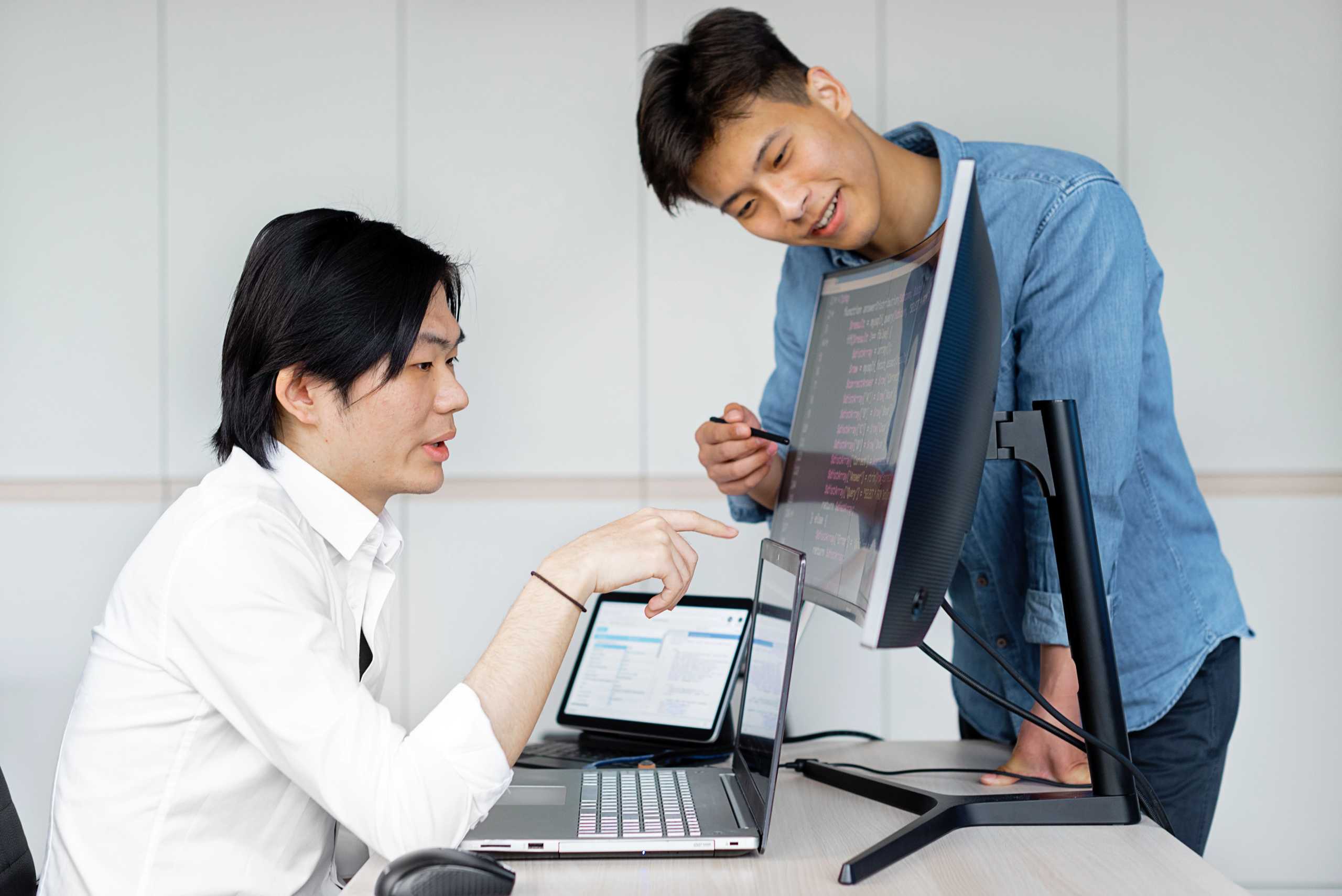 Two IT professionals reviewing technical information on a computer screen.