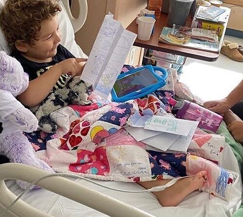 A child in a hospital bed with her quilt covering her body.