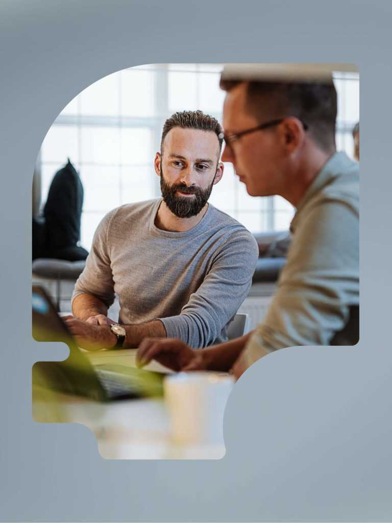 Two men work on laptops at a desk