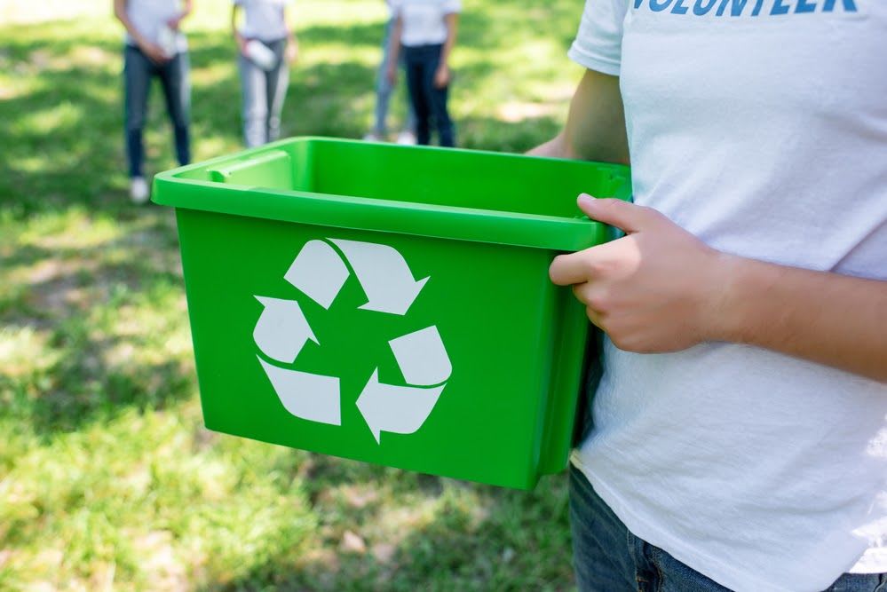 Someone holding a recycling bin.