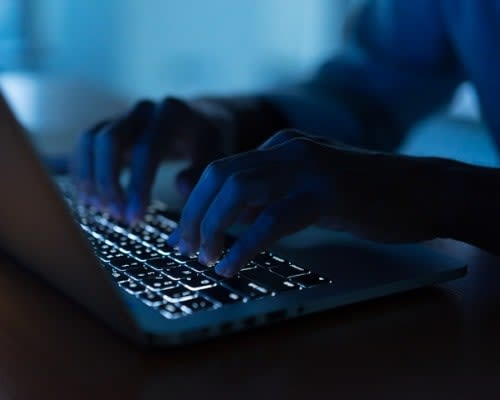 Hacker trying to Brute force attack a system, image of a hacker on a laptop typing.