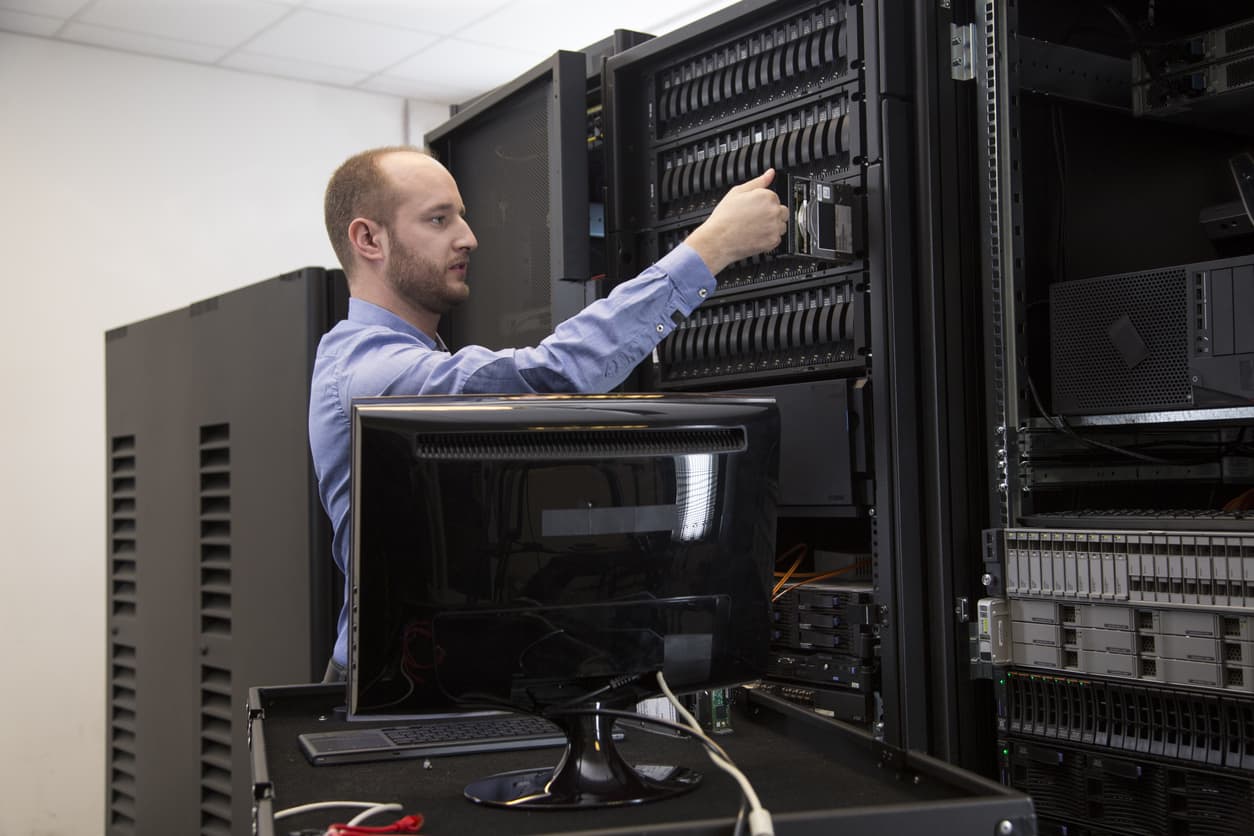 A male IT worker demonstrates data backup best practices in a server room.